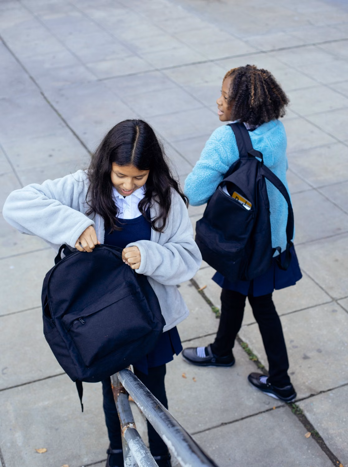 Två skolvänner med ryggsäckar utanför skolan